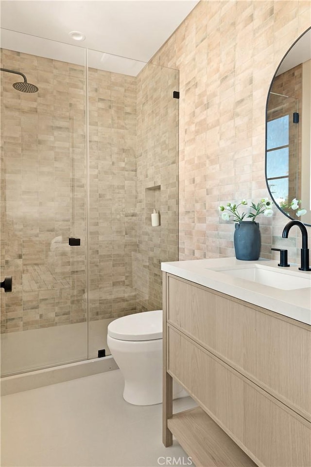 full bathroom featuring vanity, tile walls, a stall shower, and toilet