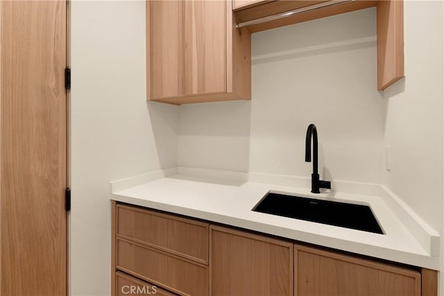 kitchen featuring light countertops, light brown cabinetry, and a sink