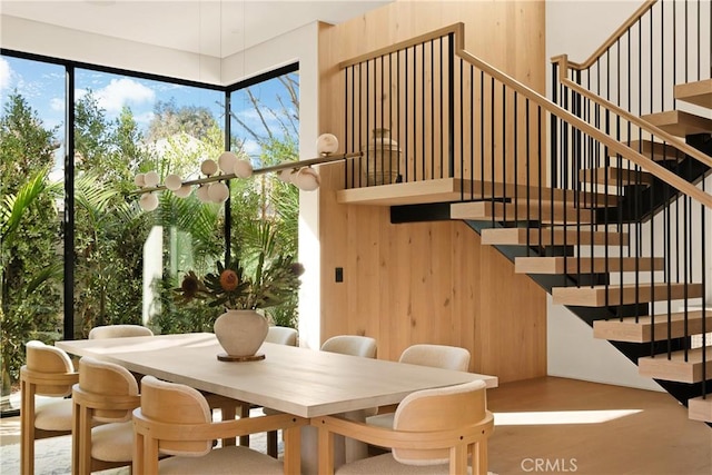 dining space with wood walls, stairs, and wood finished floors