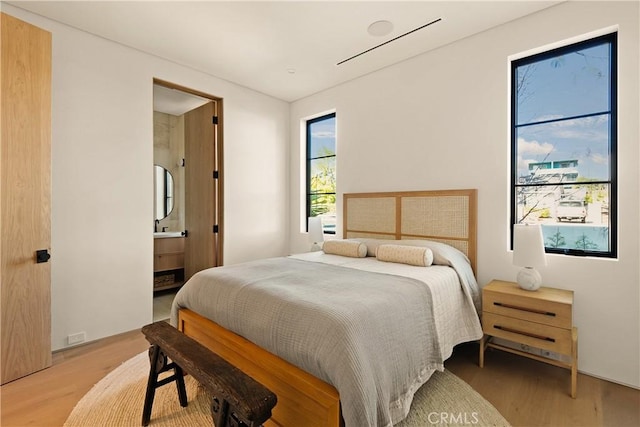 bedroom with light wood-style flooring and ensuite bath