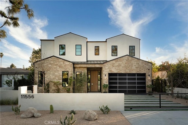 contemporary house with a fenced front yard, driveway, and stone siding