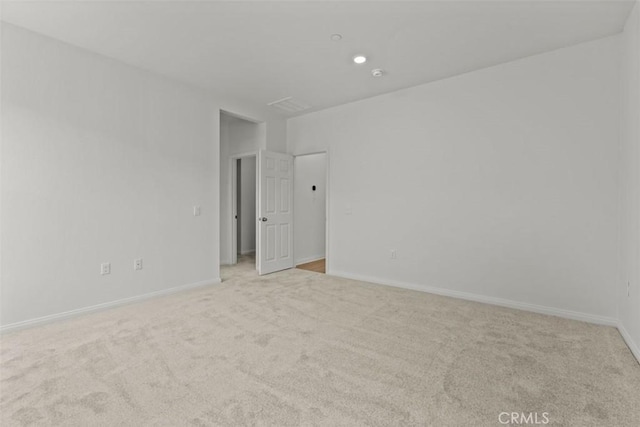 empty room featuring light colored carpet and baseboards