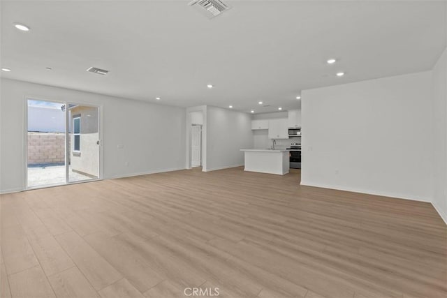 unfurnished living room featuring light wood finished floors, visible vents, a sink, and recessed lighting