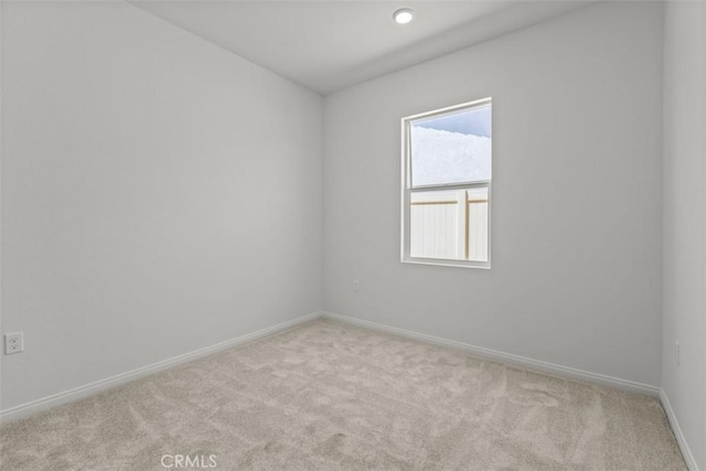 carpeted spare room featuring baseboards
