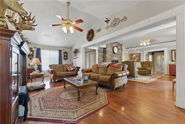 20130 Monte Vista Rd, Apple Valley, CA 92308 - living room with a ceiling fan, visible vents, vaulted ceiling, a stone fireplace, and hardwood / wood-style flooring
