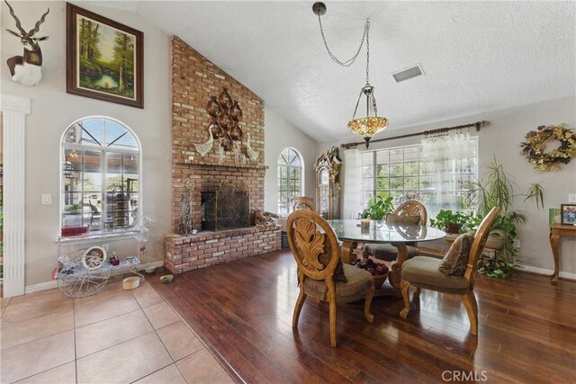 20130 Monte Vista Rd, Apple Valley, CA 92308 - dining room featuring a textured ceiling, a fireplace, vaulted ceiling, and visible vents