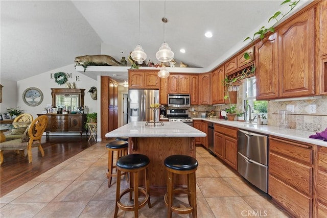 20130 Monte Vista Rd, Apple Valley, CA 92308 - kitchen with light countertops, a breakfast bar, appliances with stainless steel finishes, brown cabinets, and a kitchen island