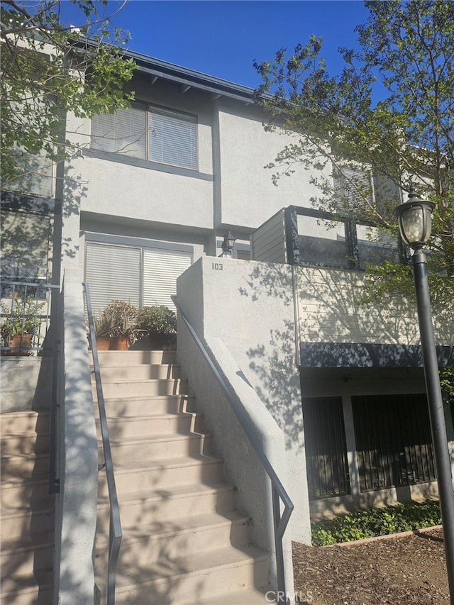 view of side of home with stairs and stucco siding