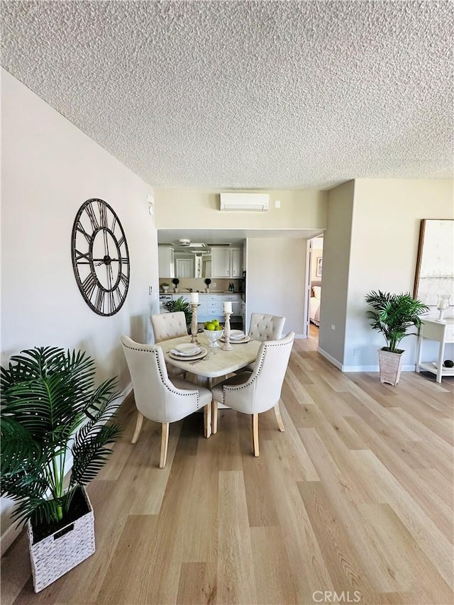 13201 El Dorado Dr Unit M9-207G, Seal Beach, CA 90740 - dining space featuring baseboards, light wood-type flooring, a wall mounted AC, and a textured ceiling