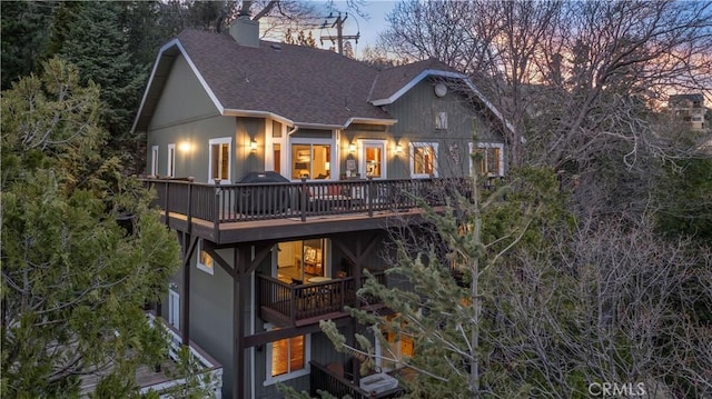 rear view of property with a chimney, a shingled roof, and a wooden deck