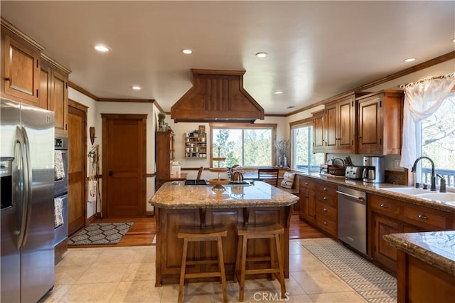 kitchen featuring stainless steel appliances, a sink, crown molding, and a kitchen island
