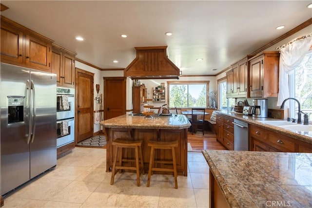 kitchen featuring plenty of natural light, brown cabinets, a sink, and appliances with stainless steel finishes