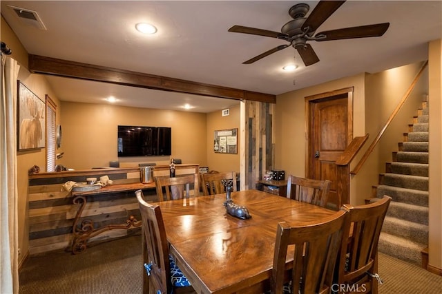 dining room featuring visible vents, a ceiling fan, carpet flooring, and stairs