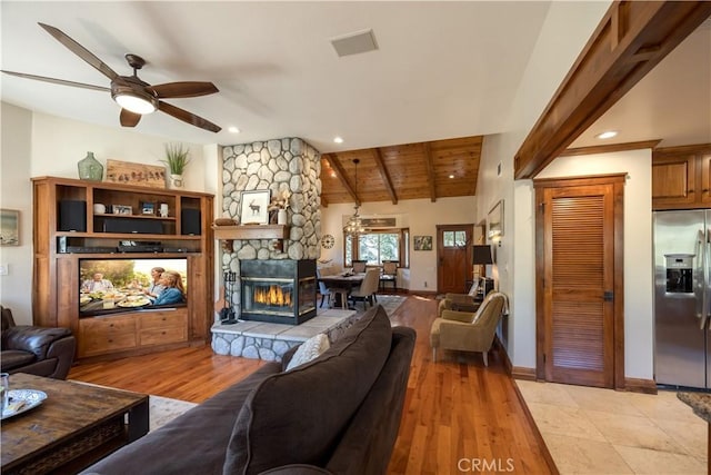 living area with ceiling fan, lofted ceiling with beams, a fireplace, light wood-style flooring, and wood ceiling