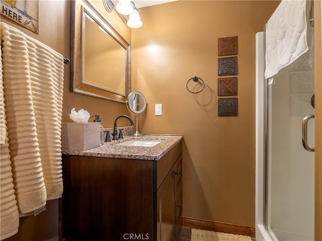 bathroom featuring baseboards, vanity, and a stall shower