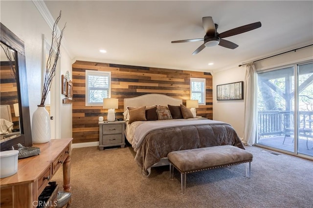 bedroom with wood walls, access to exterior, light colored carpet, and multiple windows