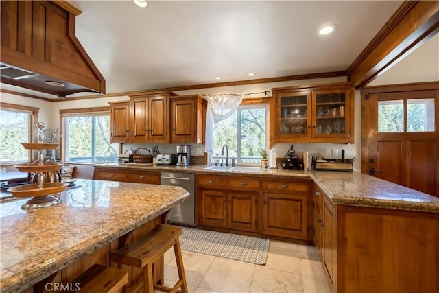 kitchen featuring a peninsula, glass insert cabinets, brown cabinetry, stainless steel dishwasher, and a sink