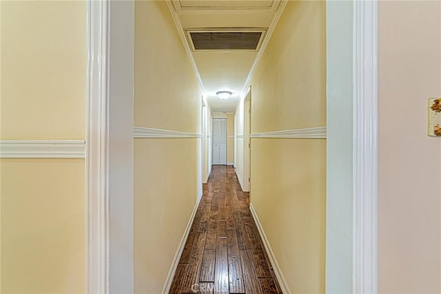 corridor featuring dark wood-style floors, ornamental molding, and baseboards