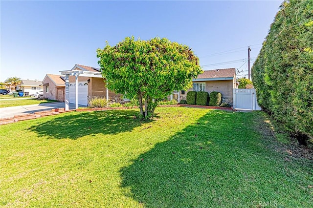 view of yard with an attached garage, a gate, and concrete driveway