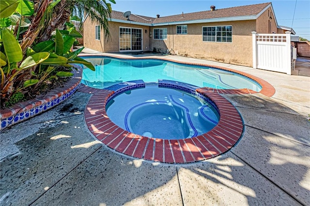 view of pool featuring a pool with connected hot tub, a patio, and fence