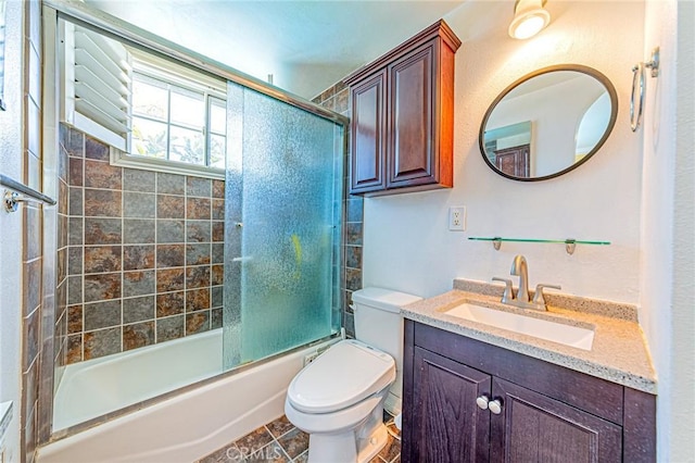 full bathroom featuring toilet, bath / shower combo with glass door, and vanity