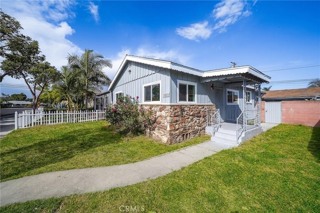 6160 California Ave, Long Beach, CA 90805 - view of front facade featuring stone siding, board and batten siding, fence, and a front lawn