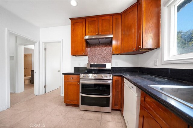 6160 California Ave, Long Beach, CA 90805 - kitchen with brown cabinetry, double oven range, under cabinet range hood, dark countertops, and white dishwasher