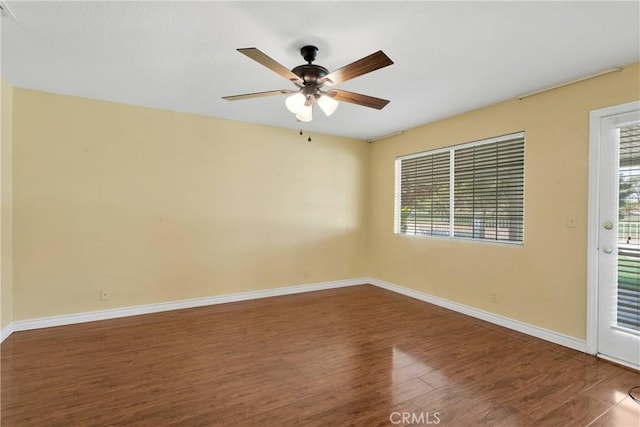 unfurnished room featuring plenty of natural light, baseboards, wood finished floors, and ceiling fan