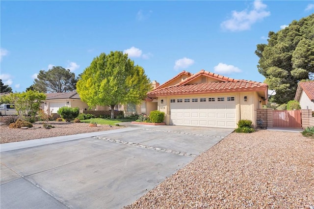 view of front facade featuring stucco siding, driveway, a tile roof, a garage, and a gate