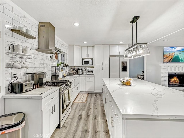 7455 Bangor Ave, Hesperia, CA 92345 - kitchen featuring stainless steel range with gas stovetop, decorative backsplash, range hood, a kitchen island, and refrigerator