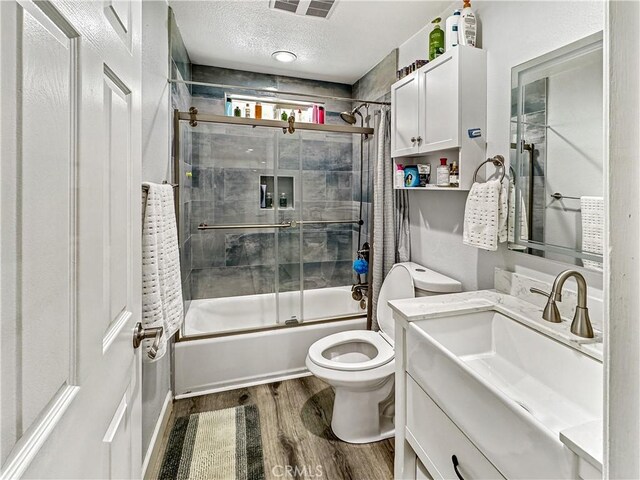 7455 Bangor Ave, Hesperia, CA 92345 - full bath with a textured ceiling, wood finished floors, vanity, combined bath / shower with glass door, and toilet