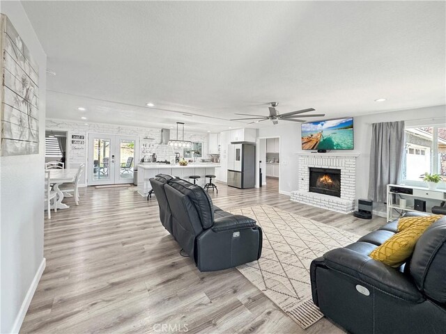 7455 Bangor Ave, Hesperia, CA 92345 - living room with a fireplace, baseboards, light wood-type flooring, a ceiling fan, and a wealth of natural light
