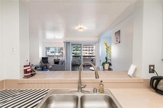 kitchen featuring open floor plan, tile countertops, and a sink