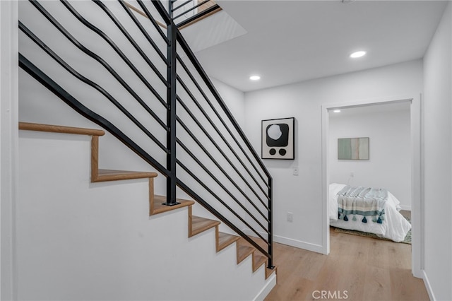 stairs with wood finished floors, baseboards, and recessed lighting