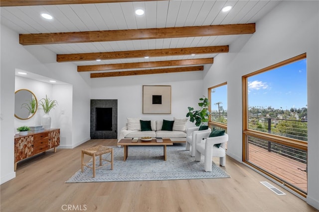 living room with baseboards, light wood-type flooring, beam ceiling, and visible vents