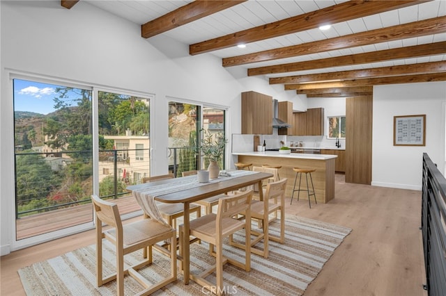 dining area with light wood-style floors, baseboards, and beam ceiling