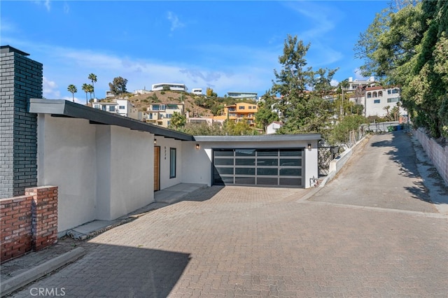 exterior space featuring driveway, fence, a garage, and stucco siding