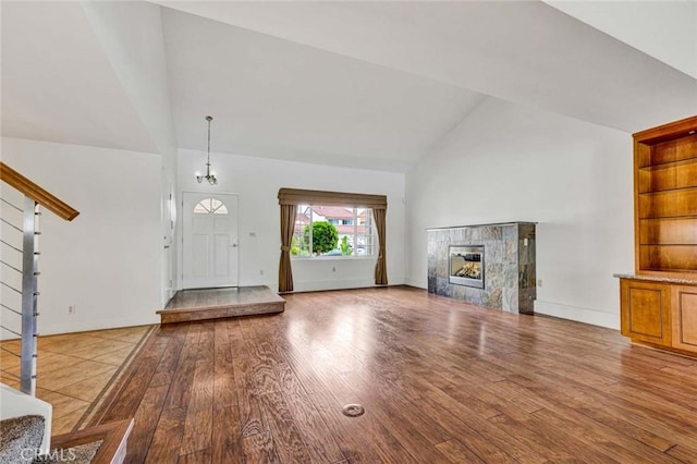 25 Bennington, Irvine, CA 92620 - unfurnished living room with baseboards, stairs, high vaulted ceiling, a tile fireplace, and wood finished floors