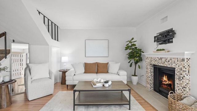 living room featuring crown molding, a fireplace, light wood finished floors, and visible vents