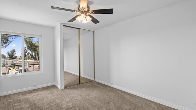 unfurnished bedroom featuring a closet, a ceiling fan, carpet, and baseboards