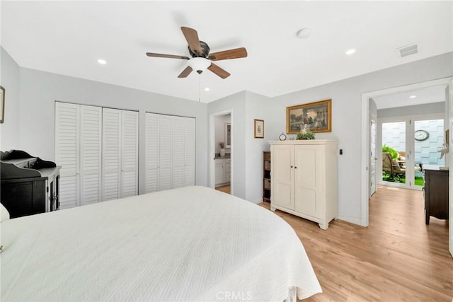 bedroom featuring visible vents, light wood-style flooring, recessed lighting, and two closets