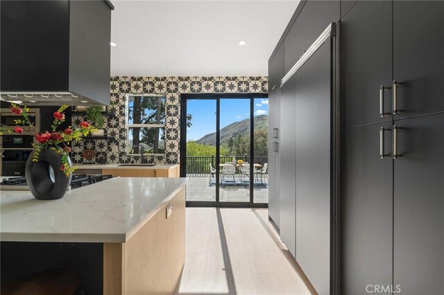 115 Buckskin Rd, Bell Canyon, CA 91307 - kitchen with wall chimney exhaust hood, a mountain view, light stone counters, paneled built in refrigerator, and modern cabinets