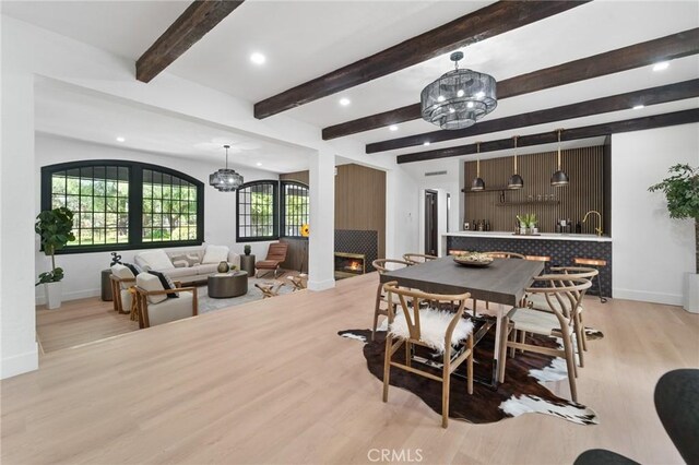 115 Buckskin Rd, Bell Canyon, CA 91307 - dining room with light wood-type flooring, a warm lit fireplace, a chandelier, baseboards, and beam ceiling