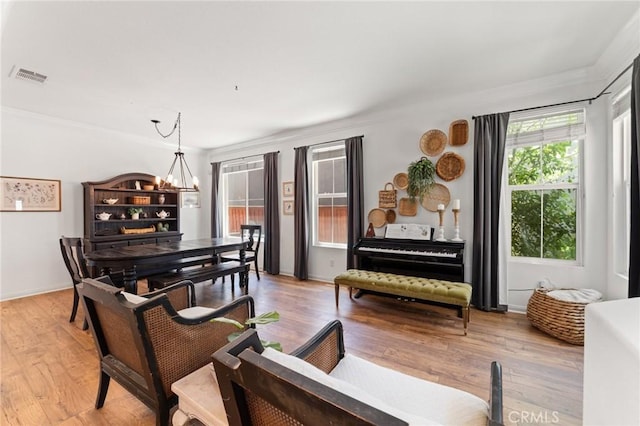 living area featuring a notable chandelier, crown molding, visible vents, and light wood-type flooring