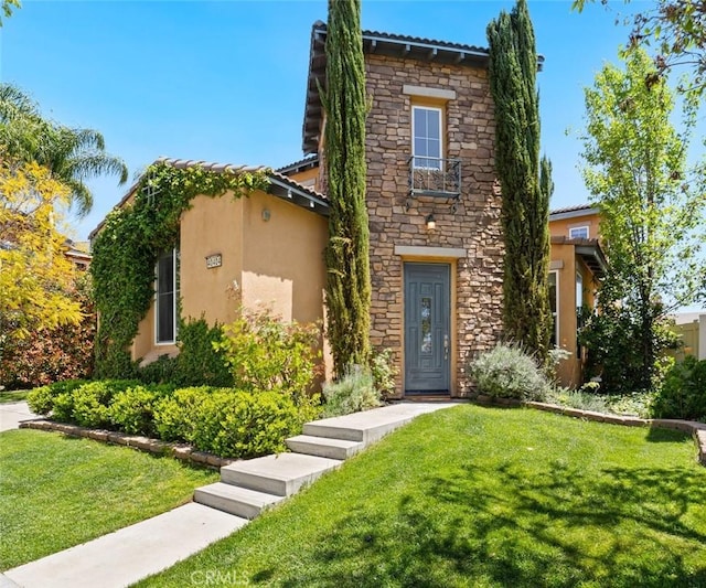 view of front facade featuring stone siding, a front yard, and stucco siding