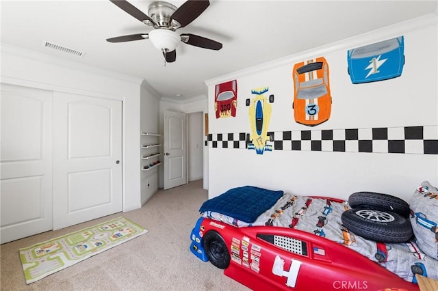 carpeted bedroom with visible vents, a closet, ceiling fan, and crown molding