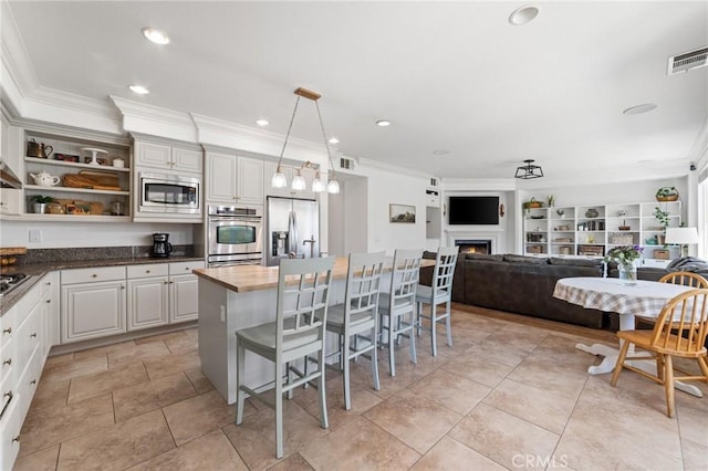 kitchen with visible vents, ornamental molding, a kitchen bar, and appliances with stainless steel finishes