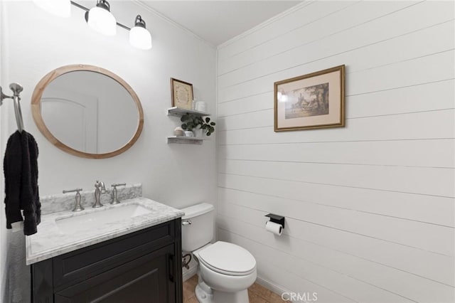 bathroom with vanity, tile patterned floors, toilet, crown molding, and wooden walls