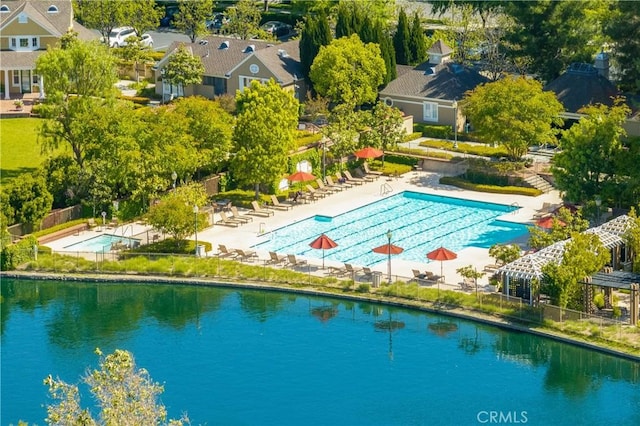 pool featuring a water view, a patio area, and fence