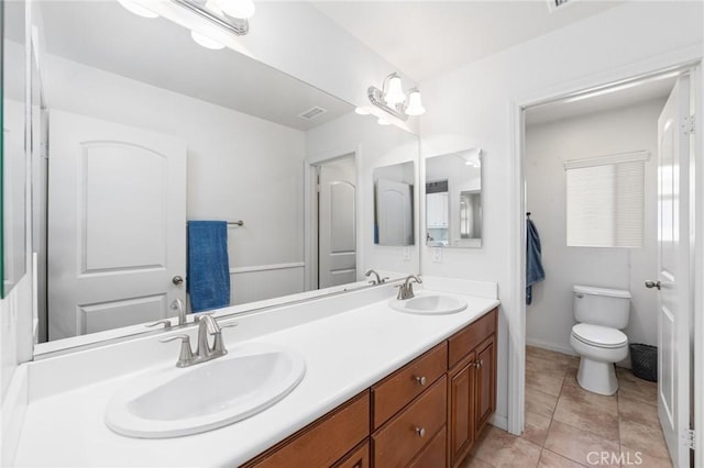 full bathroom featuring visible vents, toilet, double vanity, and a sink